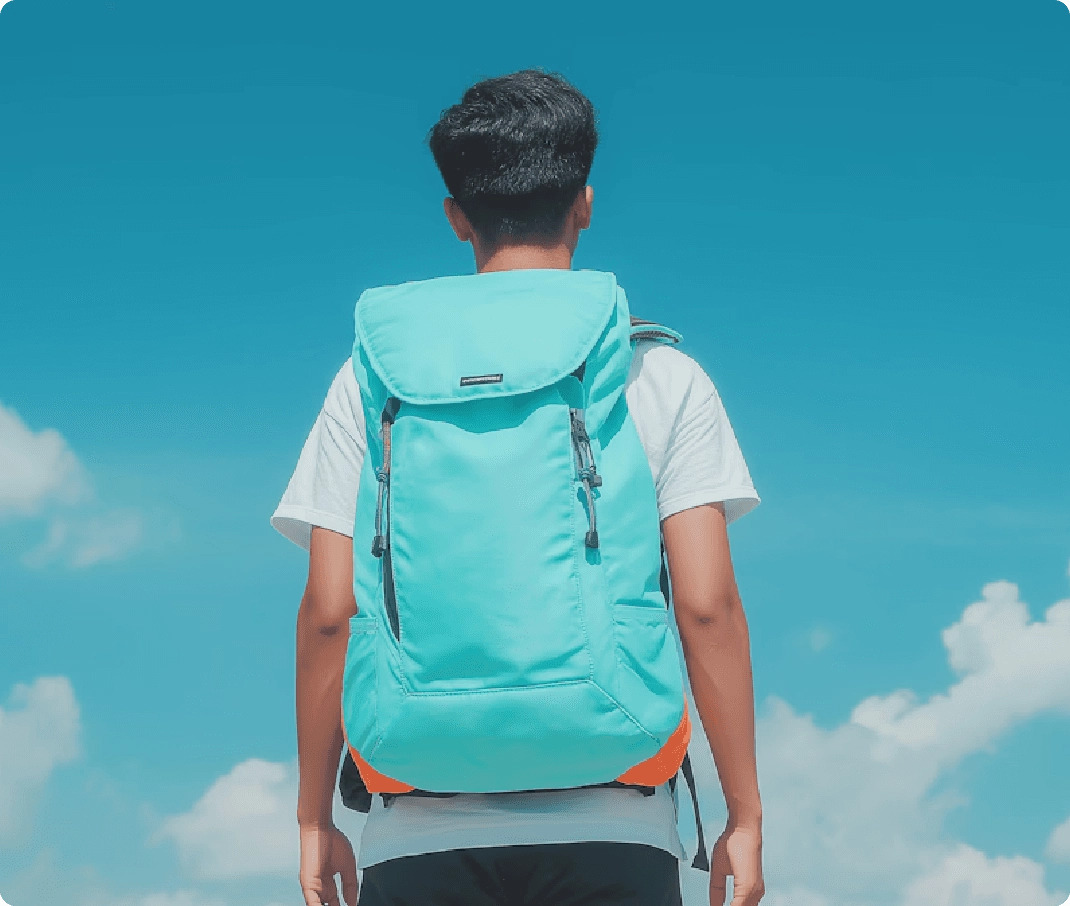 Person wearing a turquoise backpack and white t-shirt standing against a blue sky with clouds.